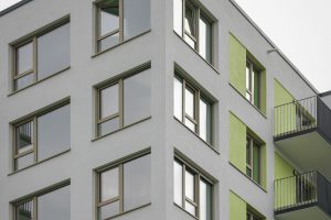 Fenster Close-up of a contemporary apartment building with unique green accents and balconies.